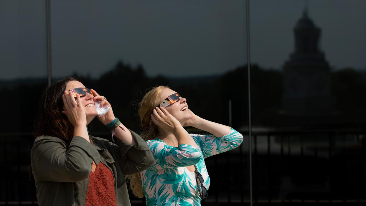  Two women observe the sun with solar eclipse glasses at SUNY Potsdam university. 