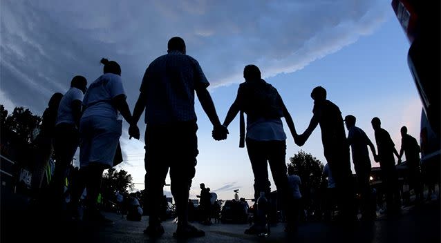 People stand in prayer after marching about a mile to the police station to protest the shooting of Michael Brown. Photo: AP