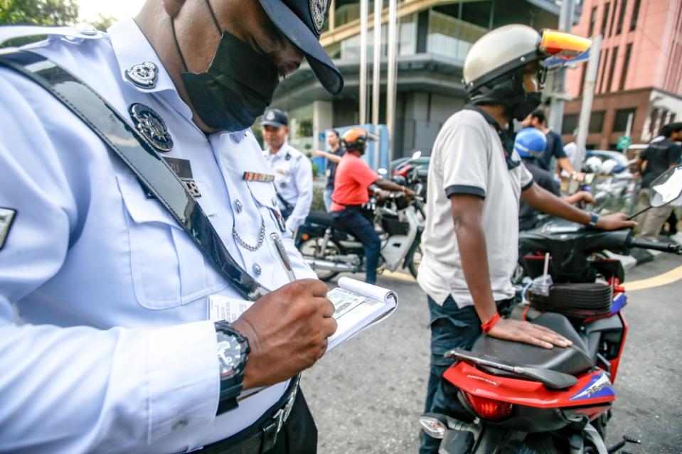 City Traffic Enforcement and Investigation Department personnel issuing summons to a motorist during a roadblock in the city centre, July 5, 2023. — Picture by Hari Anggara