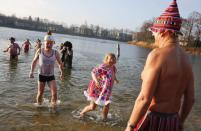 Members of the Berliner Seehunde (Berlin Seals) ice swimmers club walk out of the water after they took a dip in Lake Orankesee during their traditional New Year swimming event in Berlin, January 1, 2015. The words on the helmet (L, front) reads "The Berlin Brandenburg international airport BER is totally unsuccessful." REUTERS/Fabrizio Bensch (GERMANY - Tags: SOCIETY SPORT SWIMMING)