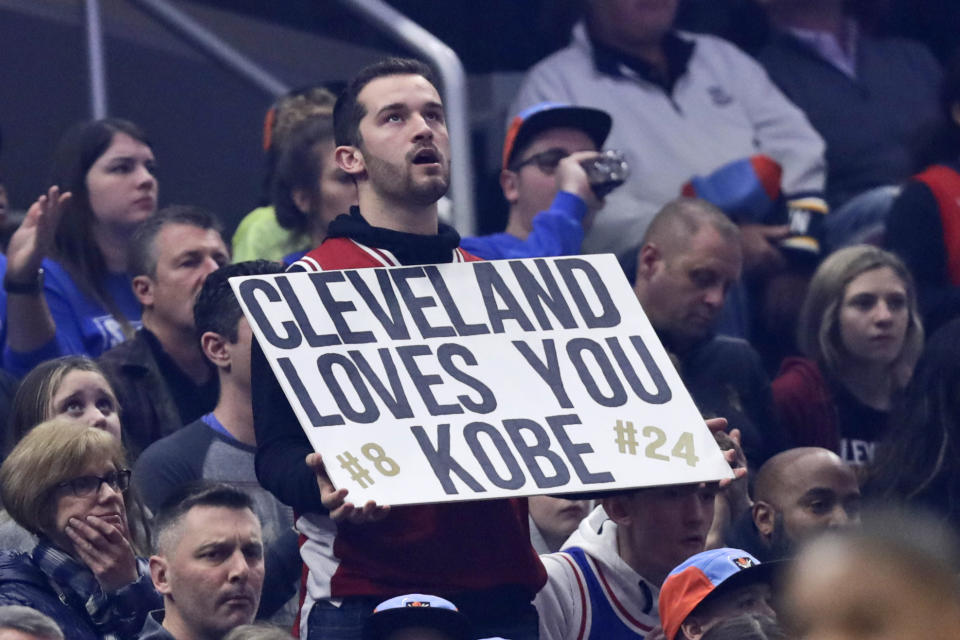 A fan holds up a sign about Kobe Bryant during the first half of an NBA basketball game between the Cleveland Cavaliers and the New Orleans Pelicans, Tuesday, Jan. 28, 2020, in Cleveland. Bryant, his 13-year-old daughter Gianna and six other passengers were killed along with the pilot Sunday. (AP Photo/Tony Dejak)