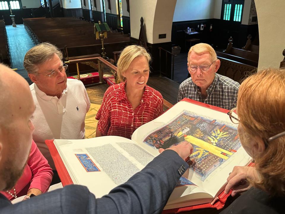 St. John’s parishioners, from left, Doug Sessions, Corinna Strayer, and Mike Fields, get a look at the Saint John's Bible ahead of a Bible reading marathon starting Aug. 24, 2023.