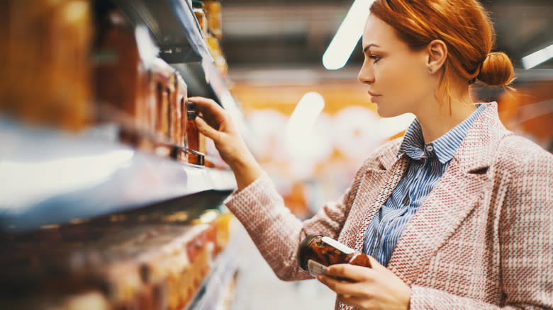 shopper holding jar of sun-dried tomatoes