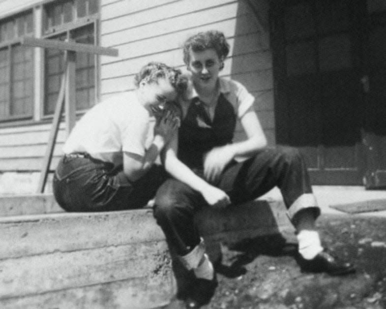 Two women photographed embracing on a stoop of a house in the US in the 1950s.