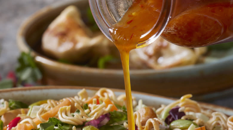 Pouring chili dressing on noodle salad