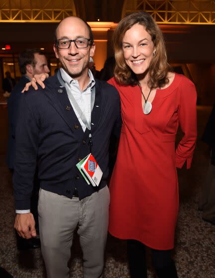 A man wearing glasses and a woman in a red dress standing next to each other