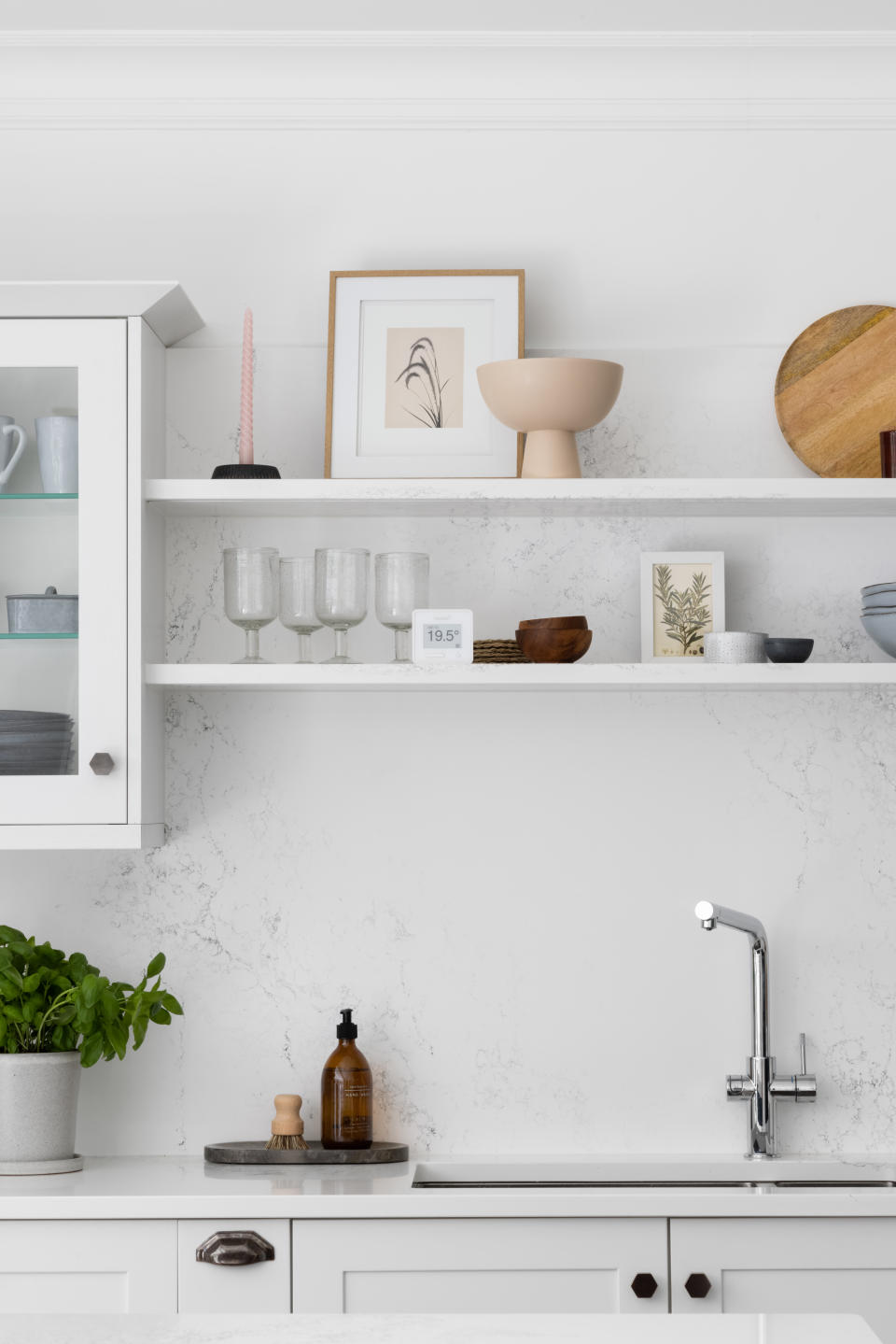 A kitchen with open shelving above a sink with chrome fittings