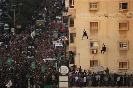 Palestinians look at Hamas militants as they rappel down a building during a military parade marking the first anniversary of the eight-day conflict with Israel, in Gaza City November 14, 2013. REUTERS/Mohammed Salem