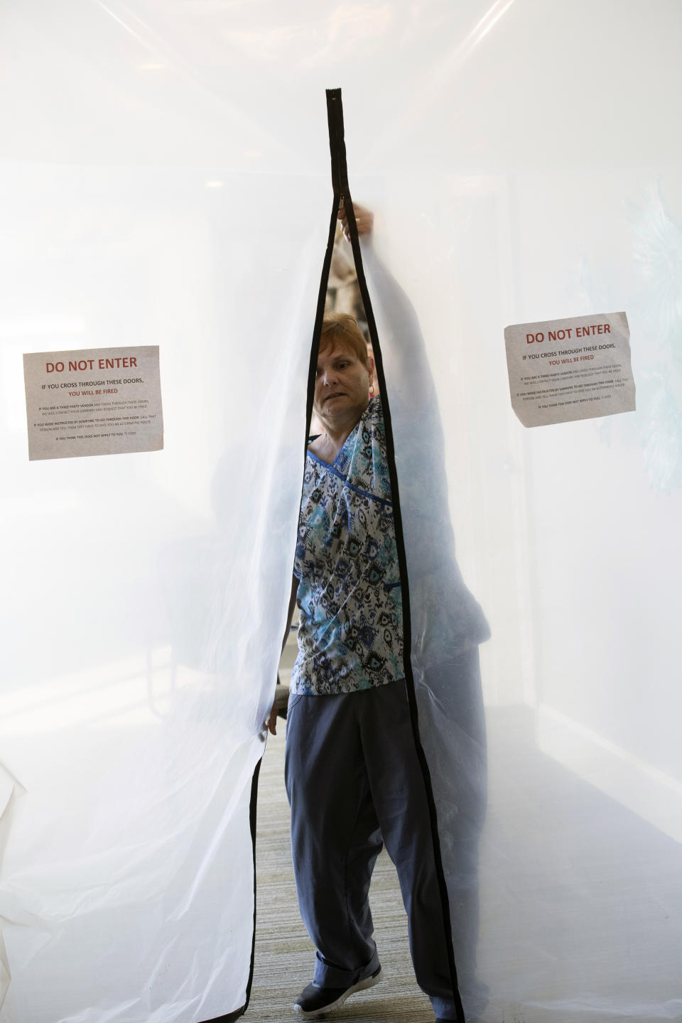 FILE - In this April 30, 2020 file photo, Donna Moore, chief operating officer of the company that runs the Park Springs senior community, zips up a door to seal off a section of a medical facility in Stone Mountain, Ga. Workers who agreed to live at a Georgia nursing home to keep its residents safe from the coronavirus will embrace their loved ones for the first time in more than two months on Saturday, June 13 as the home lifts a shelter-in-place restriction on its staff. (AP Photo/John Bazemore, File)