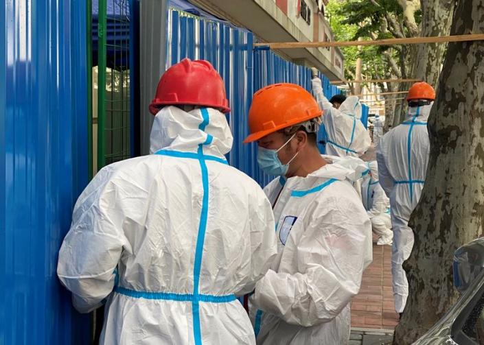 Workers in protective suits set up barriers outside a building, following the coronavirus disease (COVID-19) outbreak, in Shanghai