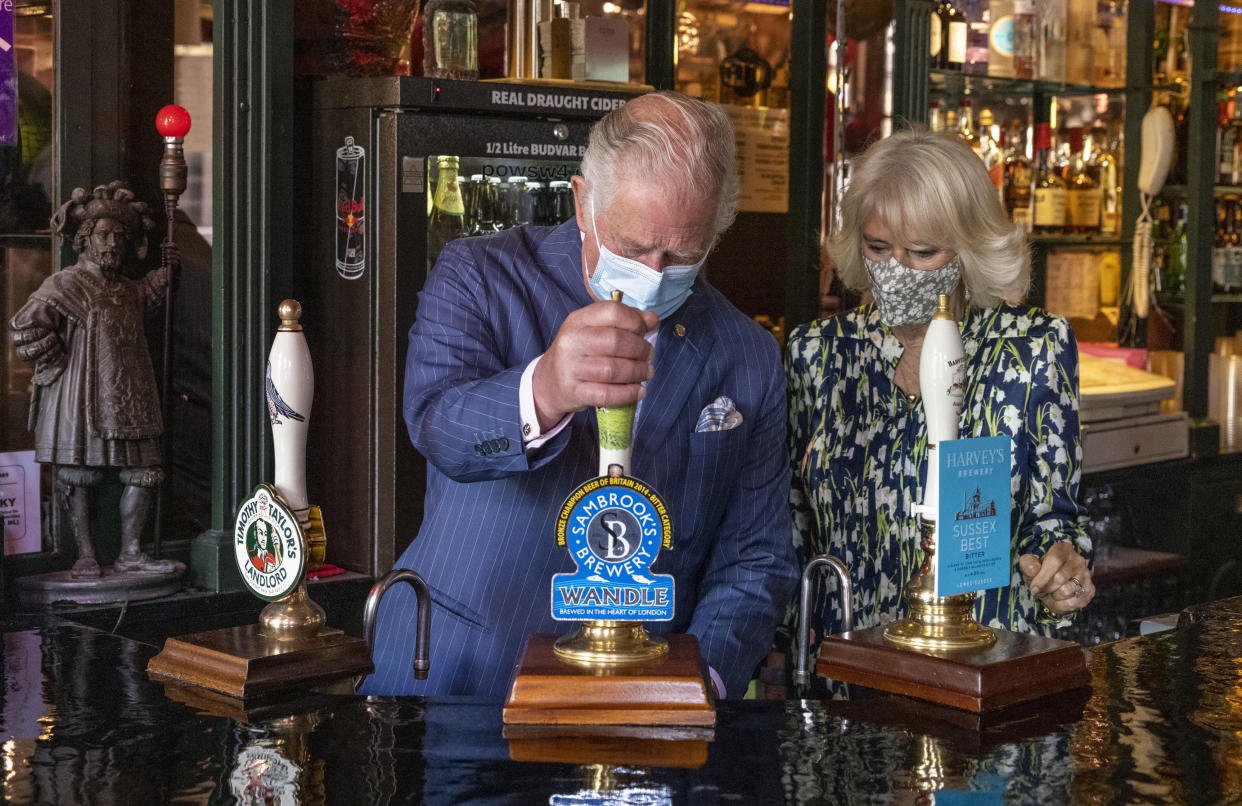 CLAPHAM, ENGLAND - MAY 27: Prince Charles, Prince of Wales pulls a pint of beer in a pub alongside Camilla, Duchess of Cornwall during a visit to Clapham Old Town on May 27, 2021 in Clapham, England. (Photo by Heathcliff O'Malley - WPA Pool/Getty Images)