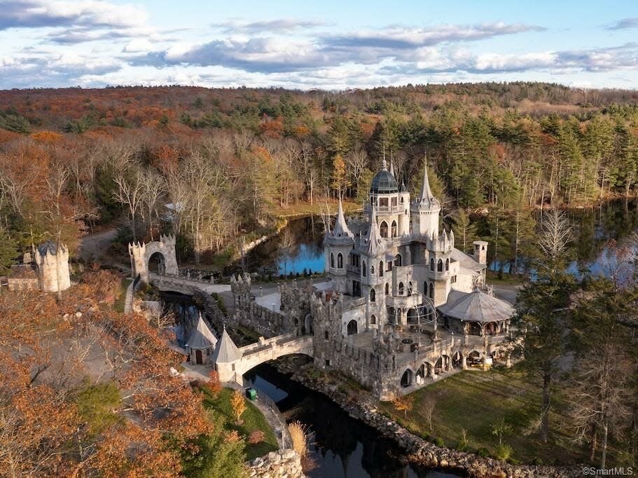 a castle with a moat and towers surrounded by water and trees in autumn in Connecticut