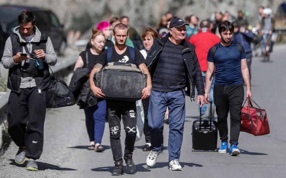 Mandatory Credit: Photo by ZURAB KURTSIKIDZE/EPA-EFE/Shutterstock (13423577n) Russian men and women with their luggage walk along a road after passing through customs at the Georgia-Russia border checkpoint of Verkhnii Lars, Georgia, 27 September 2022. Thousands of Russian men left Russia after Russian President Putin announced in a televised address to the nation on 21 September, that he signed a decree on partial mobilization in the Russian Federation due to the conflict in Ukraine. Russian Defense Minister Shoigu said that 300,000 people would be called up for service as part of the move. Georgian Interior Minister Vakhtang Gomelauri said on 27 September, that in recent days some 10,000 Russians have crossed the border with Georgia every day. On 24 February 2022 Russian troops entered the Ukrainian territory in what the Russian president declared a 'Special Military Operation', starting an armed conflict that has provoked destruction and a humanitarian crisis. Russian men flee into neighboring Georgia following Russia's partial military mobilization announcement, Verkhnii Lars - 27 Sep 2022  - ZURAB KURTSIKIDZE/EPA-EFE/Shutterstock