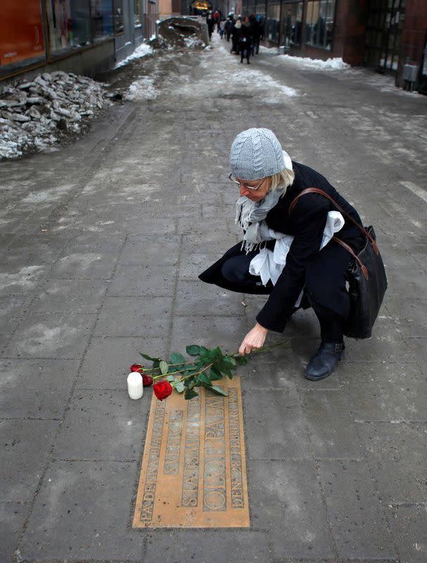 FILE PHOTO: A women lays a rose on a plaque marking the location where Swedish Prime Minister Olof Palme was killed 25 years ago in Stockholm