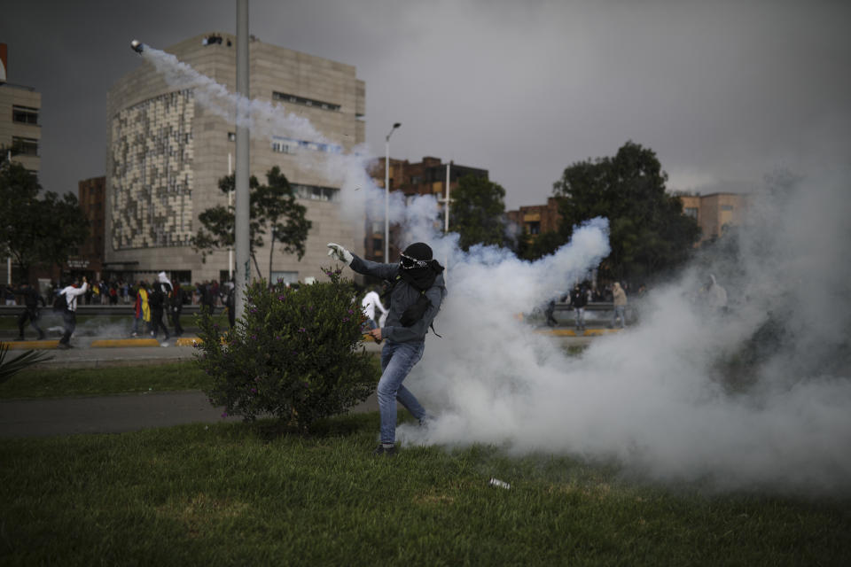 An anti-government protester throws a tear gas canister back at the police during a protest in Bogota, Colombia, Thursday, Nov. 21, 2019. Colombia's main union groups and student activists called for a strike to protest the economic policies of Colombian President Ivan Duque government and a long list of grievances. (AP Photo/Ivan Valencia)