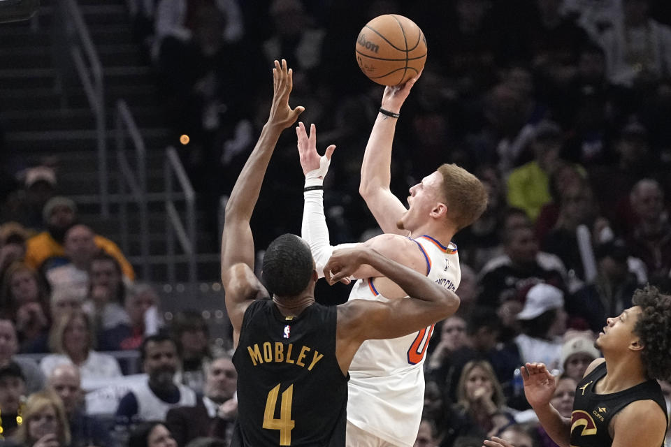 New York Knicks guard Donte DiVincenzo (0) shoots in front of Cleveland Cavaliers forward Evan Mobley (4) in the second half of an NBA basketball game, Sunday, March 3, 2024, in Cleveland. (AP Photo/Sue Ogrocki)