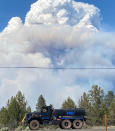 In this photo provided by the Bootleg Fire Incident Command, columns of smoke from the Bootleg Fire rise behind a water tender in southern Oregon on Friday, July 16, 2021. Firefighters scrambled Friday to control a raging inferno in southeastern Oregon that's spreading miles a day in windy conditions, one of numerous wildfires across the U.S. West that are straining resources. The Bootleg Fire, the largest wildfire burning in the U.S., has torched more than 377 square miles (976 square kilometers), and crews had little control of it. (Lisa Chambers/Bootleg Fire Incident Command via AP)