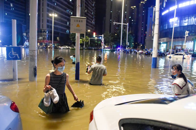 People wade through floodwater at an intersection after heavy rainfall led to flooding in Hefei