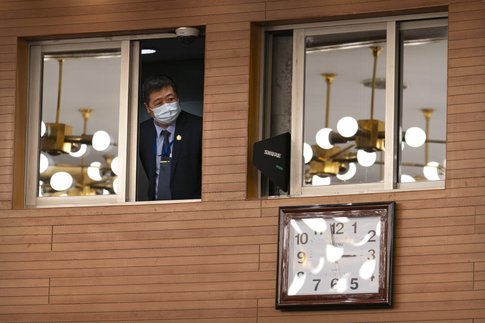 A staff member looks out from a control room before a remote video press conference by Chinese Foreign Minister Wang Yi held on the sidelines of the annual meeting of China's National People's Congress (NPC) in Beijing, Sunday, March 7, 2021. (AP Photo/Mark Schiefelbein)