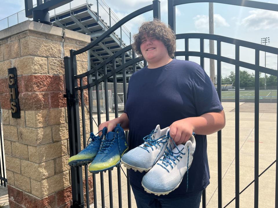 Eric Kilburn Jr. with two pairs of his new custom-made cleats from Under Armour, ready for football practice at Goodrich High School Aug. 21, 2023. The sophomore, who is 6 foot, 10 inches tall and outgrew his size 22 shoes, has had a whirlwind past five months after his mother shared their struggle to find shoes that fit.