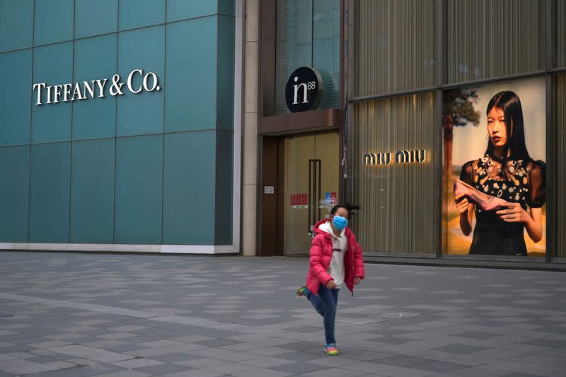 FILE PHOTO: Child wearing a face mask runs past stores of Tiffany & Co and Miu Miu, as the country is hit by an outbreak of the novel coronavirus, in Beijing