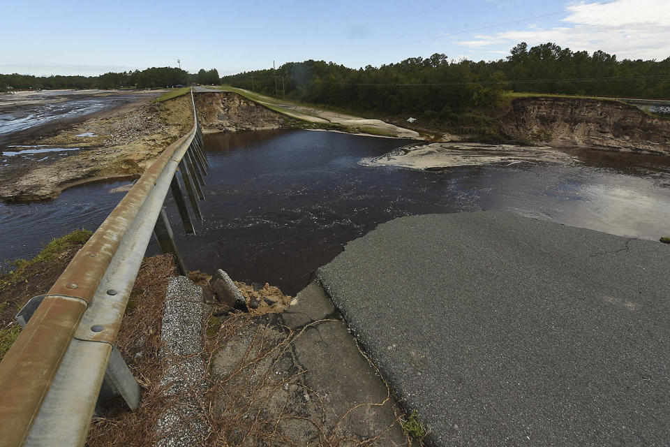 Water runs through a damaged roadway from Hurricane Florence at Alton Lennon Drive in Boiling Spring Lakes, N.C. ,Tuesday Sept. 18, 2018. (Ken Blevins /The Star-News via AP)