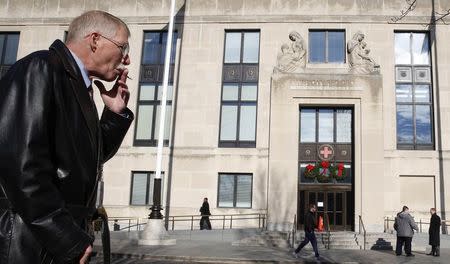 A cigarette smoker stands in the designated smoking area across from the National Headquarters of the American Red Cross in Washington, December 30, 2014. REUTERS/Larry Downing