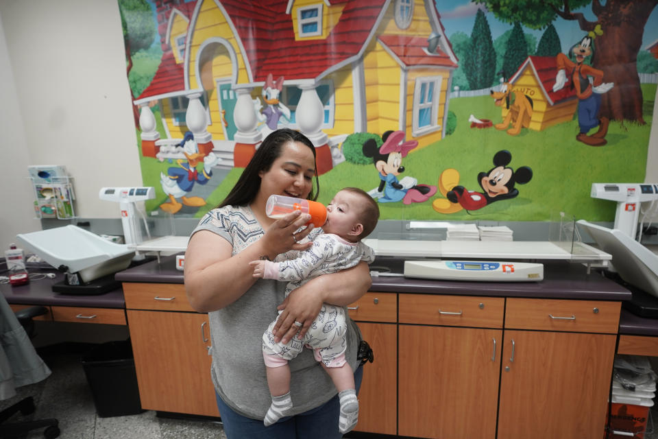 Elizabeth Amador bottle feeds her daughter Destinee, 9 months, at the Ellis R. Shipp Public Health Center Thursday, May 12, 2022, in West Valley City, Utah. President Joe Biden stepped up his administration's response to a nationwide baby formula shortage Thursday, May 12, 2022, that has forced frenzied parents into online groups to swap and sell to each other to keep their babies fed. (AP Photo/Rick Bowmer)