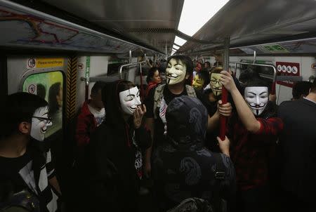 Pro-democracy protesters wearing Guy Fawkes masks take a subway train to a protest site occupied by them as part of the Occupy Central civil disobedience movement in Hong Kong November 5, 2014, the day marking Guy Fawkes Night. REUTERS/Bobby Yip