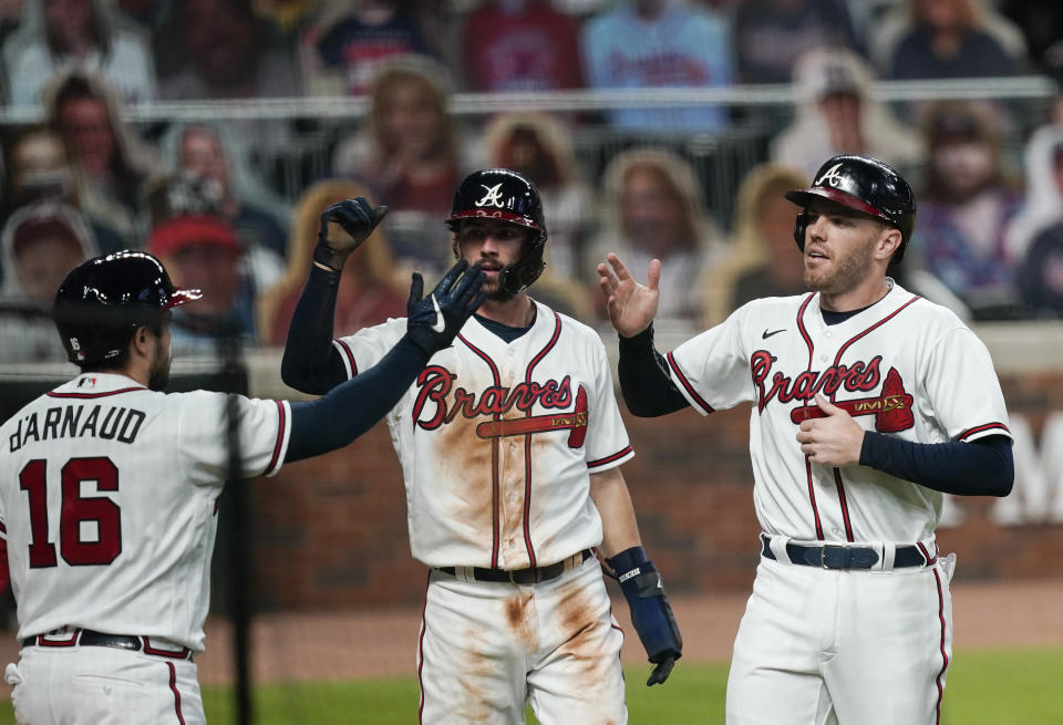 Atlanta Braves' Dansby Swanson, center, and Adam Duvall, right, celebrate with Travis d'Arnaud, left, after scoring on a double hit by teammate Marcell Ozuna in the fifth inning of a baseball game against the Tuesday, Sept. 22, 2020, in Atlanta. (AP Photo/Brynn Anderson)