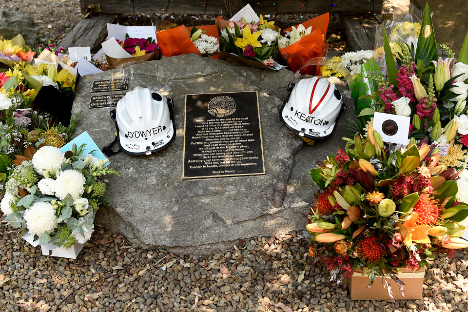 Flowers and the helmets of volunteer firefighters Andrew O'Dwyer and Geoffrey Keaton are seen at the memorial at the Horsley Park Rural Fire Brigade. Source: AAP