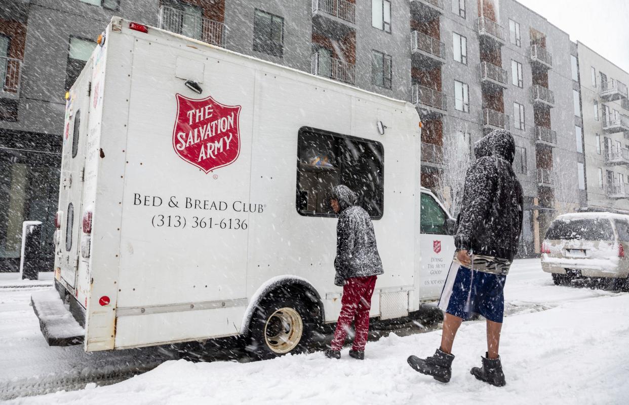 Detroit residents line up outside the Bed & Bread truck belonging to the Salvation Army Detroit Harbor Light to get food, clothing, and other essential items on a snowy day in Detroit on Wednesday, Jan. 25, 2023. 