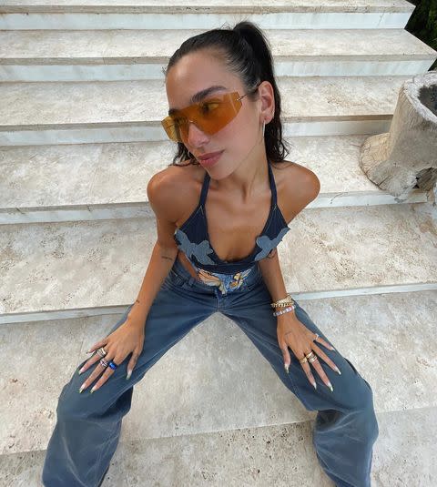 <p>Dua Lipa is continuing to hit it out of the park when it comes to her styling this summer. After celebrating her 26th birthday, the singer shared a picture of her 1990s-inspired double denim look on Instagram, featuring a denim halter-neck top from Yung Reaper with patchwork butterflies, a pair of baggy, high-waisted denim jeans by Eytys and orange frameless sunglasses.</p><p><a class="link " href="https://yungreaper.com/collections/frontpage/products/butterfly-denim-top" rel="nofollow noopener" target="_blank" data-ylk="slk:SHOP DUA'S DENIM TOP">SHOP DUA'S DENIM TOP</a></p><p><a href="https://www.instagram.com/p/CTAV2aiMGzx/" rel="nofollow noopener" target="_blank" data-ylk="slk:See the original post on Instagram" class="link ">See the original post on Instagram</a></p>