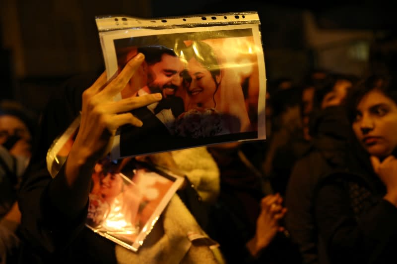 A woman holds a picture of newlyweds, victims of the crash of the Boeing 737-800 plane, flight PS 752, as people gather to show their sympathy in Tehran