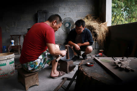 Owner Tian Huan (R) chats with a blacksmith at his workshop for handmade woks in Datian village, Hubei province, China August 13, 2018. REUTERS/Thomas Suen