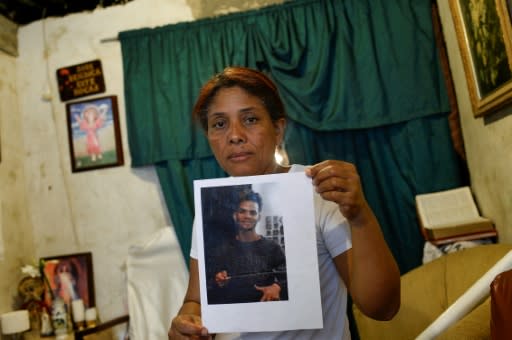 Carmen Arroyo, whose son Cristian was killed in September 2018, poses holding his picture at her home in the Petare slum, Caracas