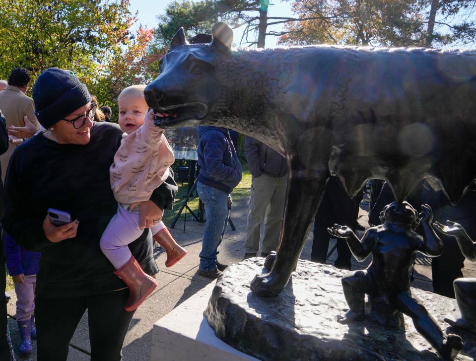 Maggie Berolo of Cleves and her daughter, Enza, 18 months old, get a close look at the Capitoline Wolf unveiled by Cincinnati Parks on Friday. The bronze statue was stolen during its 90th birthday month in June 2022. The local lodge of Sons and Daughters of Italy helped raise funds to replace it.