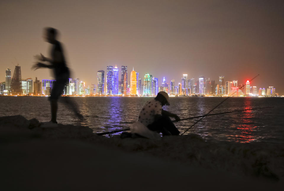 In this Nov. 2, 2018 picture men fish, backdropped by the city skyline Doha, Qatar. Eight stadiums scattered in a 30-mile radius that will host 32 teams from across the planet are in various stages of development, most of them trying to walk the treacherous line of paying homage to the region's history while simultaneously avoiding becoming an expensive and unused relic once the party ends and everyone else goes home. (AP Photo/Vadim Ghirda)