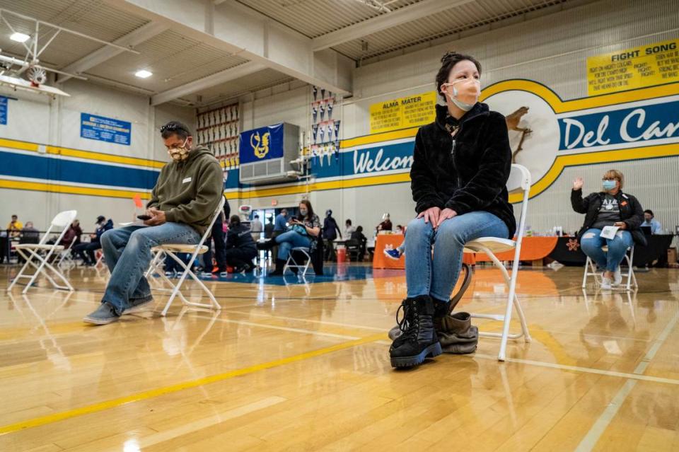 Alexandra Sargent, right, an office assistant at St. Elizabeth Ann Seton School in Elk Grove, sits in a waiting area where people are monitored for 15 minutes for any side effects after receiving the COVID-19 vaccine, Saturday, Feb. 20, 2021, at Del Campo High School in Fair Oaks, during a vaccine clinic held by the San Juan Unified School District in partnership with Dignity Health.