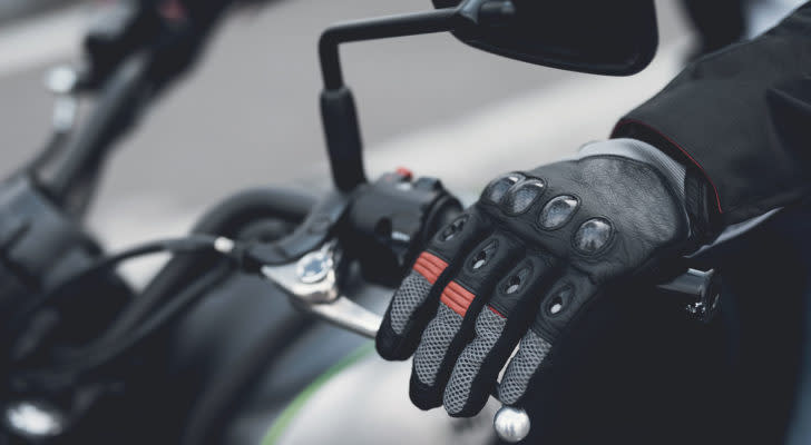 A photo of a gloved hand on the helm of a motorcycle.