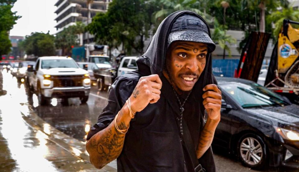 Steven Camillus Hall Jr., 30, of Miami, covers himself from the rain while walking along Brickell Plaza across from Brickell City Centre in Miami on Wednesday, November 15, 2023.