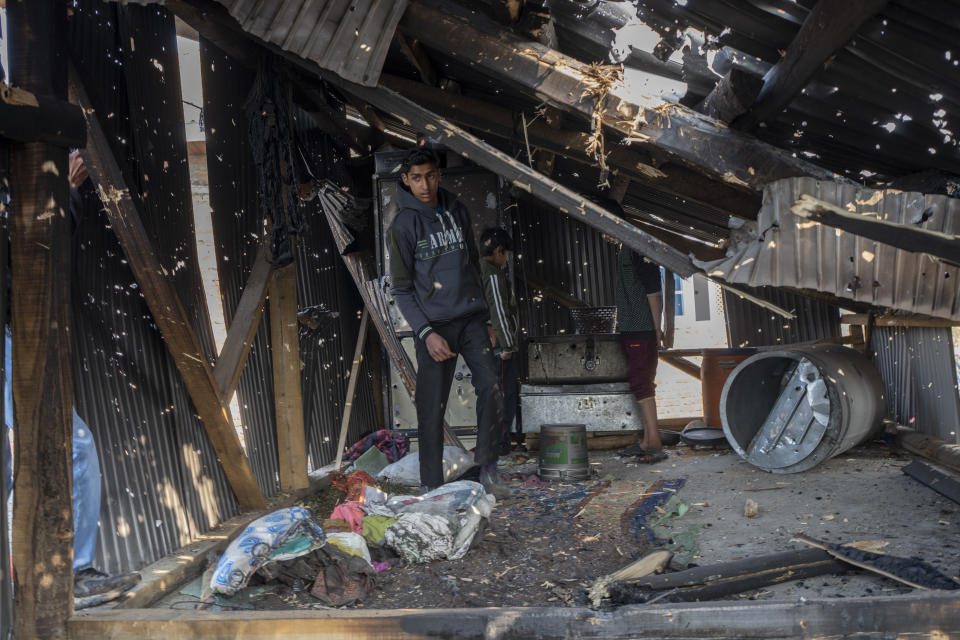 A Kashmiri boy stands under the bullet ridden tin roof of a damaged residential house where suspected rebels had taken refuge, after a gunfight in Kulgam south of Srinagar, Indian controlled Kashmir, Friday, Nov. 17, 2023. Police in Indian-controlled Kashmir said government forces killed five suspected militants in a gunbattle on Thursday.(AP Photo/Dar Yasin)