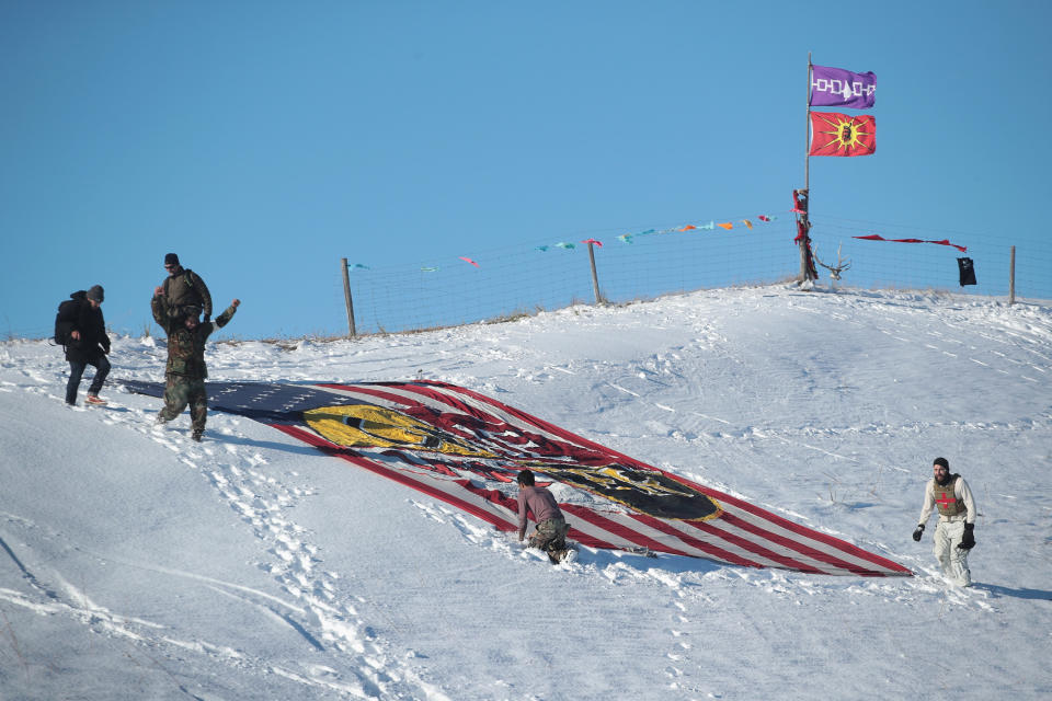 Military veterans place a flag that says 'one water' on a hillside above Oceti Sakowin Camp on the edge of the Standing Rock Sioux Reservation on December 4, 2016 outside Cannon Ball, North Dakota. (Photo: Scott Olson via Getty Images)