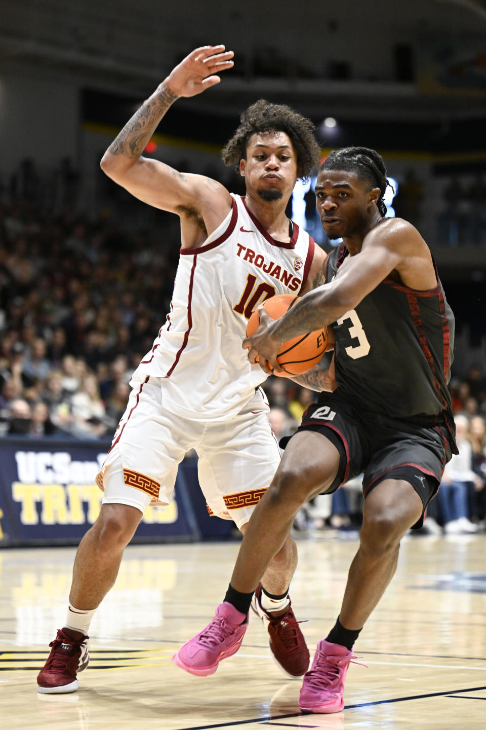 Oklahoma guard Otega Oweh (3) drives past Southern California forward DJ Rodman (10) during the second half of an NCAA college basketball game Friday, Nov. 24, 2023, in San Diego. (AP Photo/Denis Poroy)