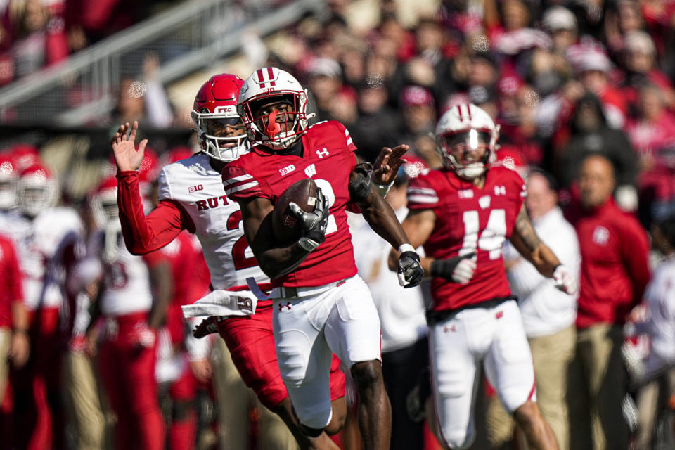 Wisconsin cornerback Ricardo Hallman (2) returns an interception 95-yards for touchdown as Rutgers quarterback Gavin Wimsatt, left, chases during the first half of an NCAA college football game Saturday, Oct. 7, 2023, in Madison, Wis. (AP Photo/Andy Manis)
