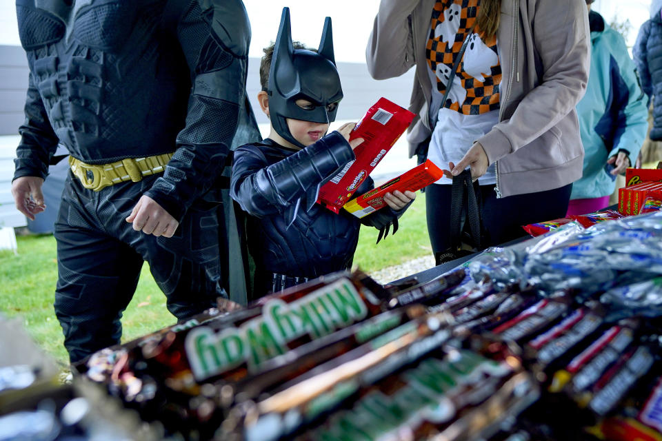 Parents and children get free Halloween candy from a local businessman, Tuesday, Oct. 31, 2023, in Lewiston, Maine. Locals seek a return to normalcy after a shooting that claimed multiple lives in their community on Oct. 25. The deadliest shooting in Maine's history stunned a state of 1.3 million people that has relatively little violent crime. (AP Photo/Matt York)