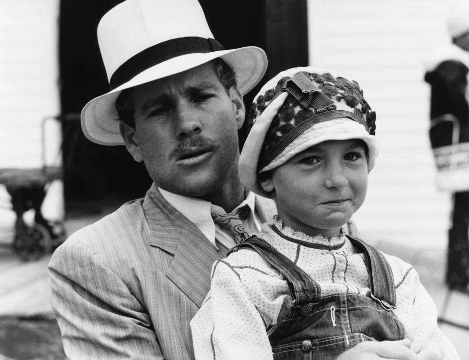 Paul Newman in a pinstripe suit and hat holding little girl Jackie Gleason wearing overalls and a bonnet