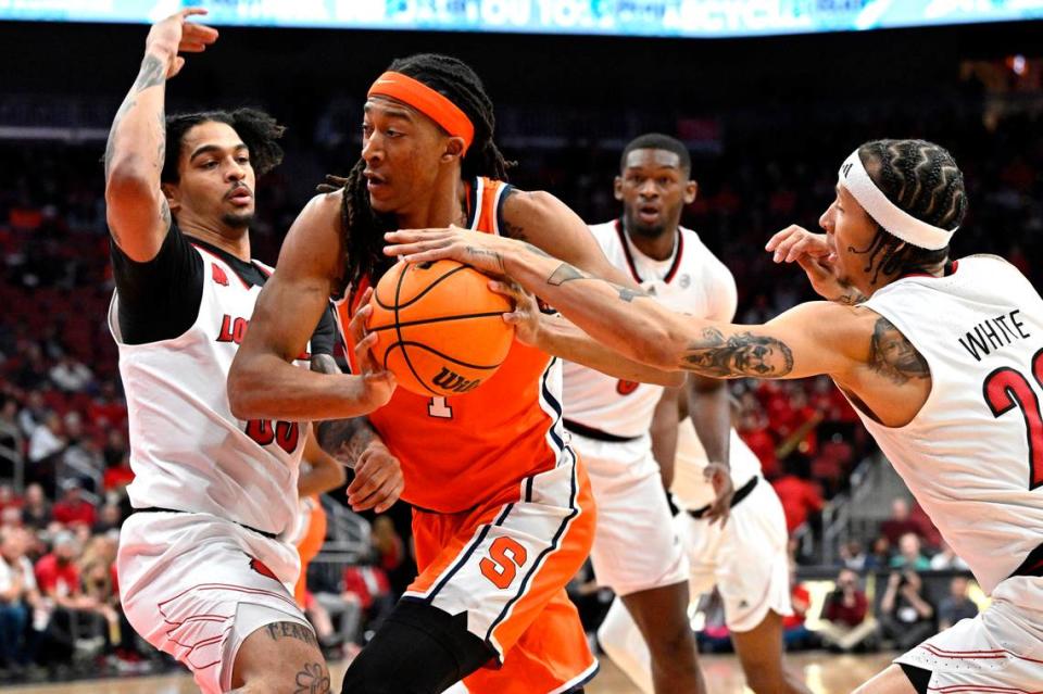 Syracuse’s Maliq Brown (1) drives to the basket as Louisville’s Tre White (22) and Skyy Clark (55) during their game at KFC Yum! Center in March 2024.