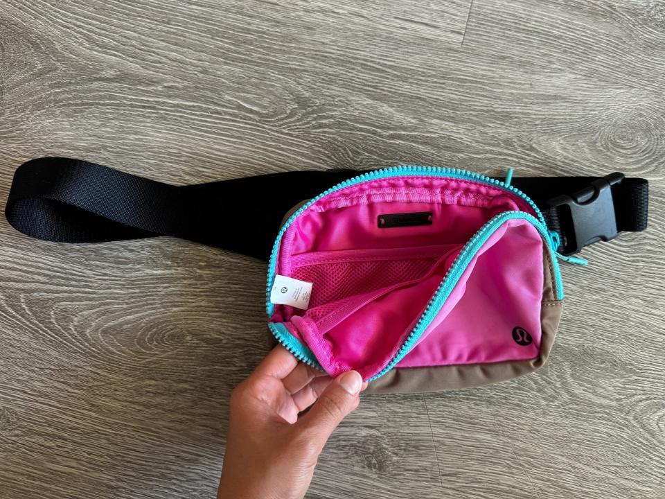 hand opening a pink lululemon crossbody bag