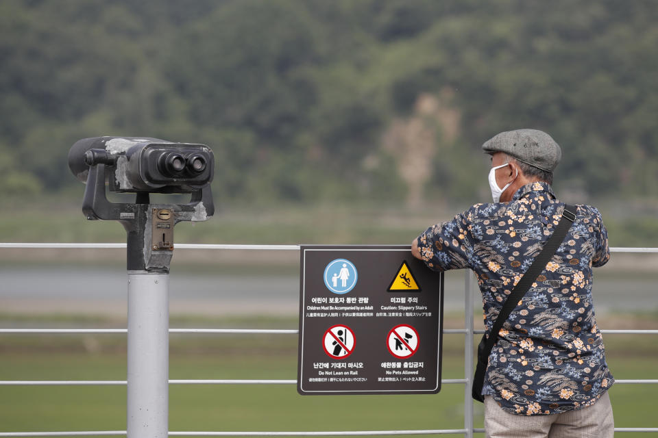 A visitor wearing a face mask watches the northern side from the Imjingak Pavilion in Paju, South Korea, Sunday, June 14, 2020. South Korea on Sunday convened an emergency security meeting and urged North Korea to uphold reconciliation agreements, hours after the North threatened to demolish a liaison office and take military action against its rival. (AP Photo/Lee Jin-man)